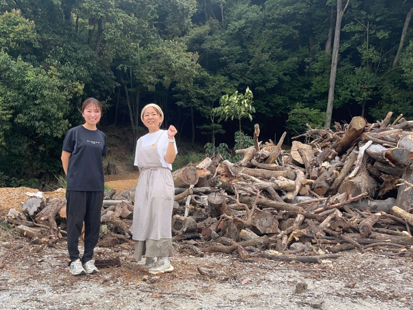 薪の山の前に立つ里弥さんとトコ